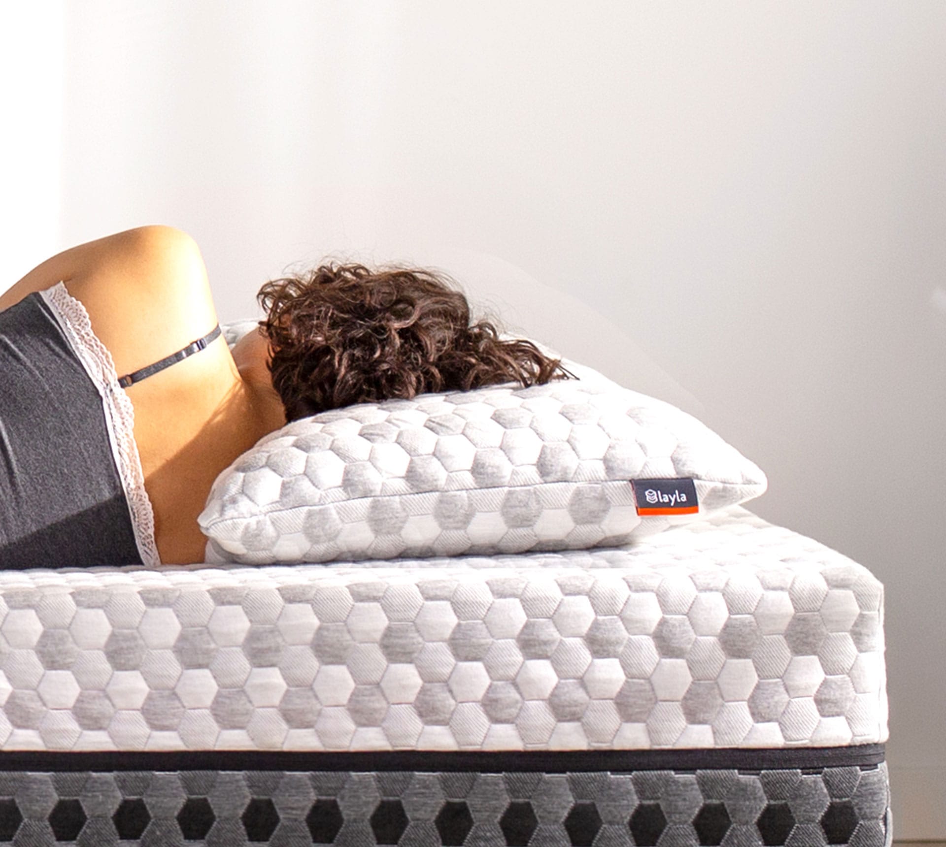 Woman laying down on a mattress, resting her head on a Kapok Pillow