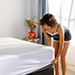 Woman putting the cooling protector on a mattress